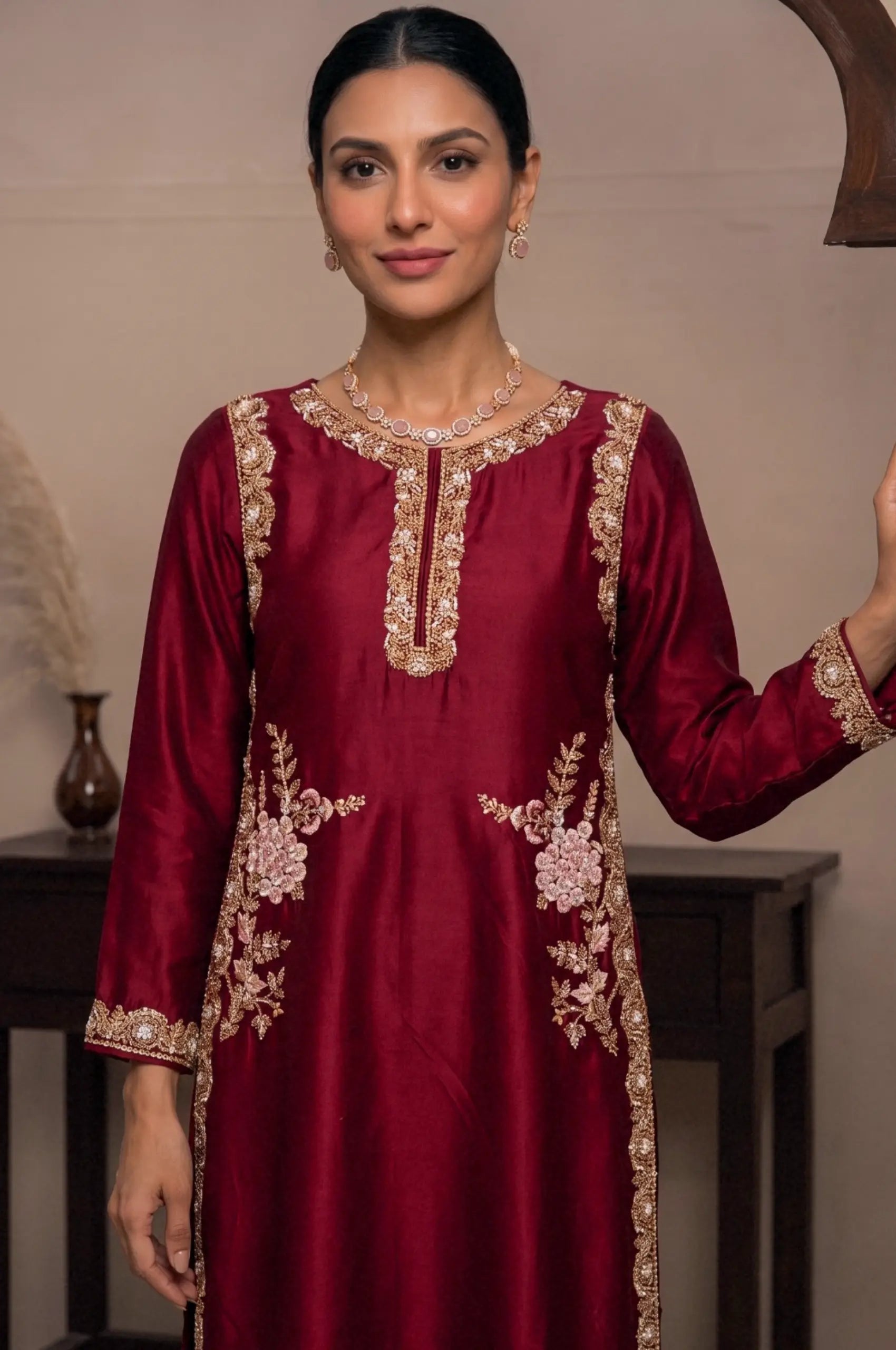 Model posing in a long maroon kurti featuring a gold border and side embroidery.