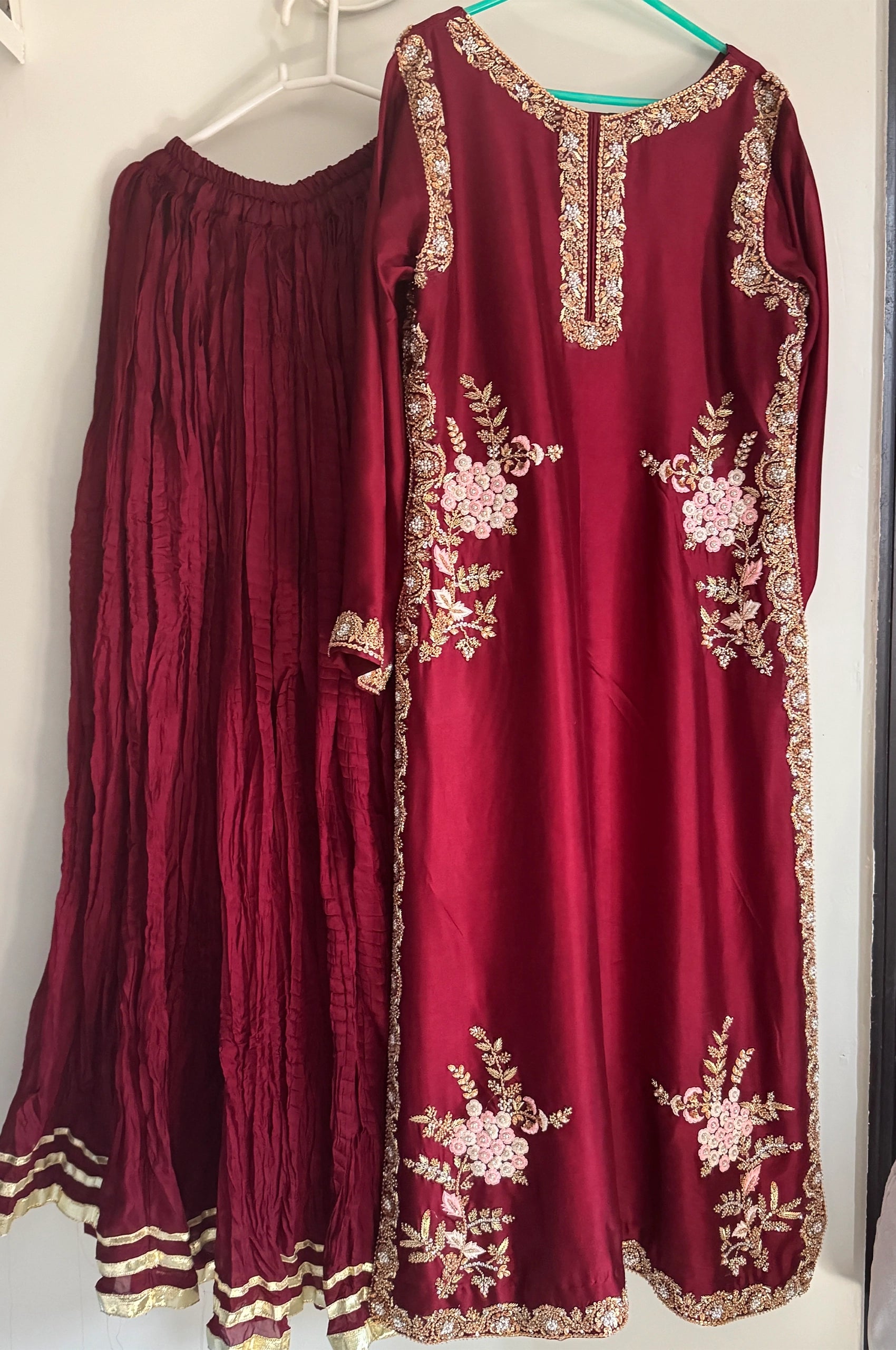 Maroon embroidered long kurti and matching flared skirt displayed on hangers.
